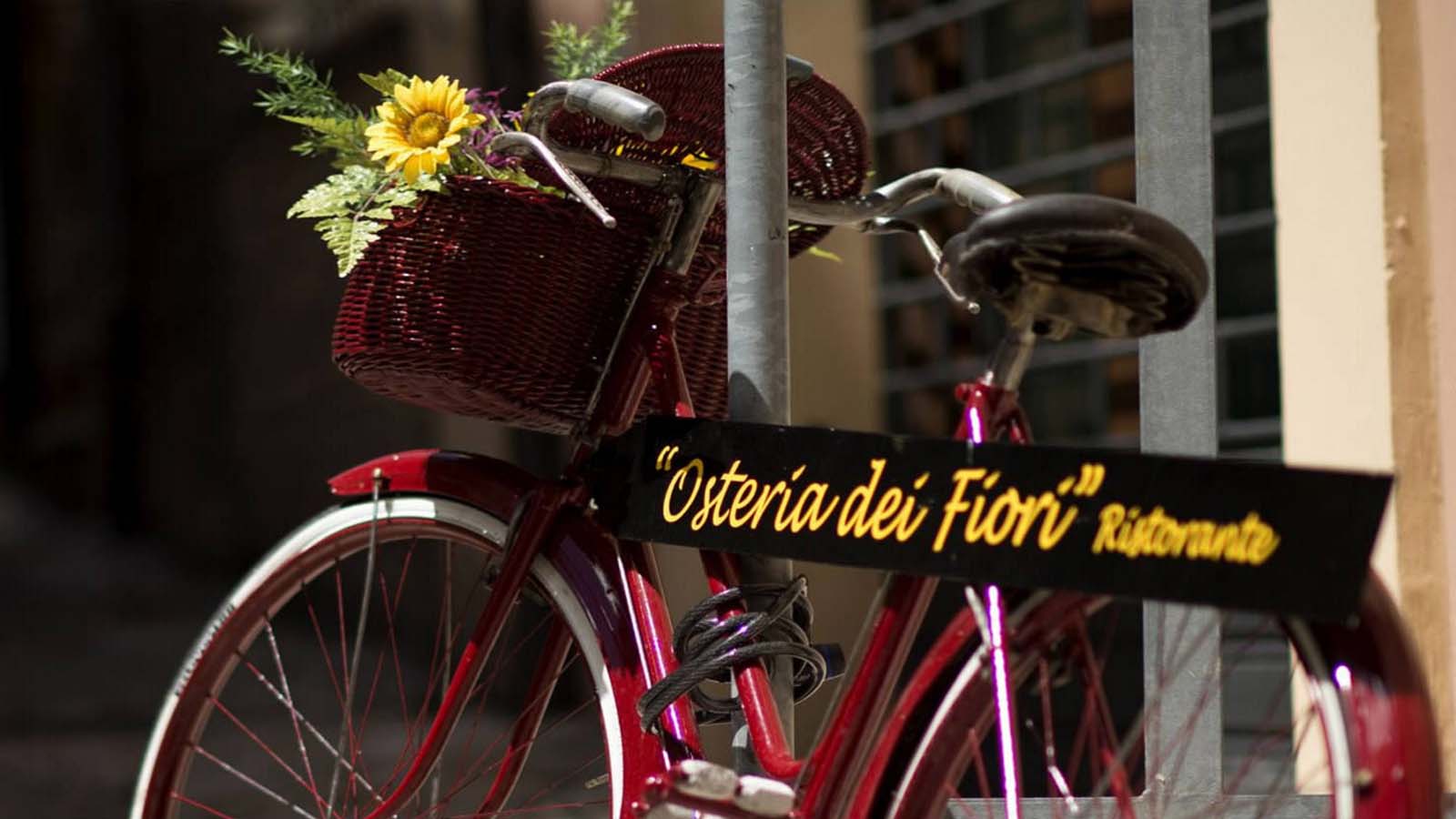 Bicicletta rossa con bouquet di fiori e cartello che indica la direzione del ristorante.
